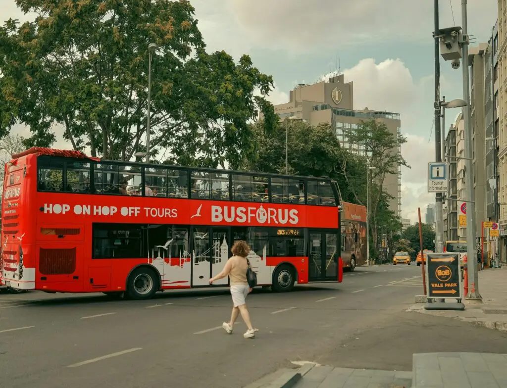 Tourists enjoy a double decker tour bus ride in a bustling city area.