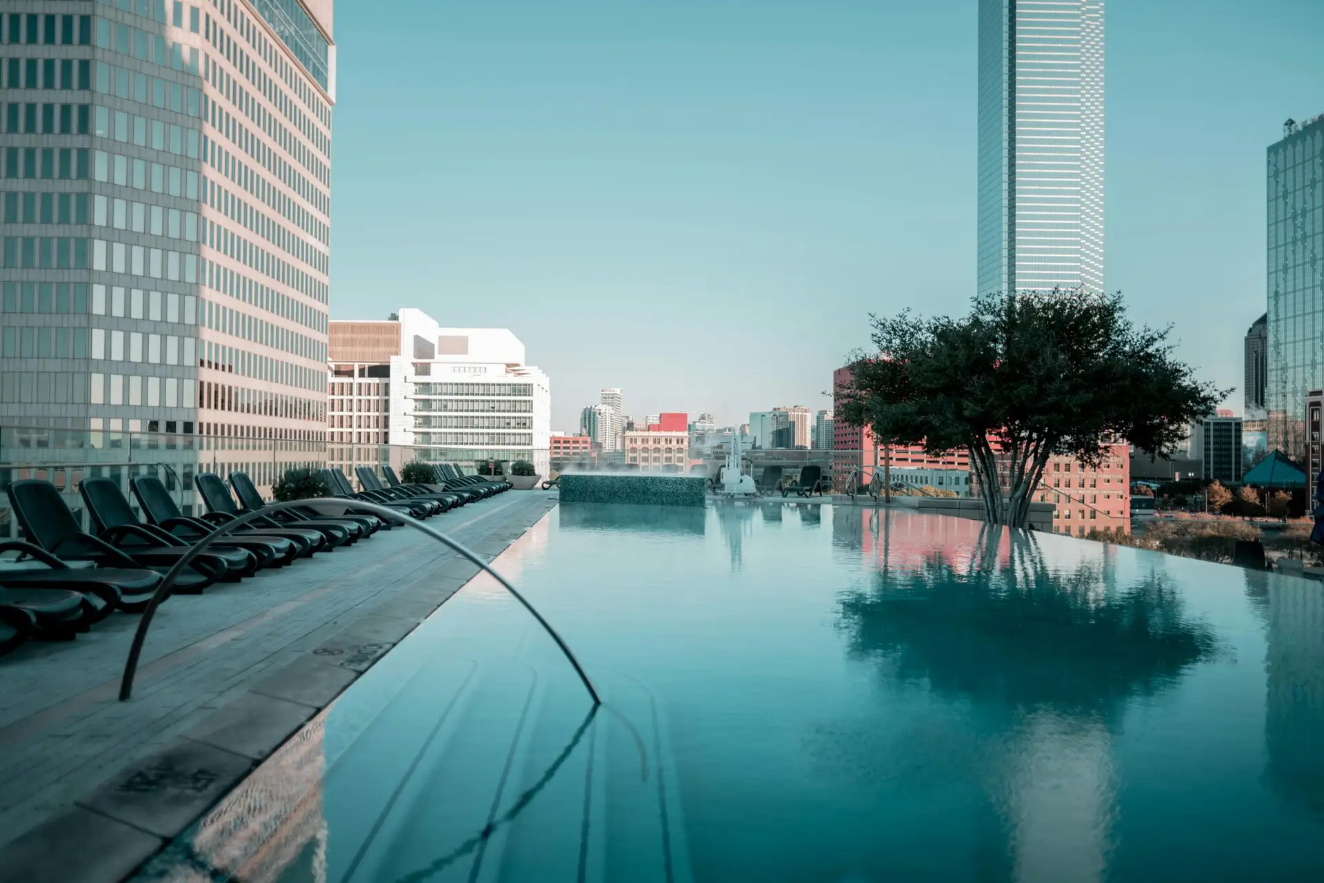 Rooftop infinity pool with city skyline and lounge chairs offering a tranquil escape.