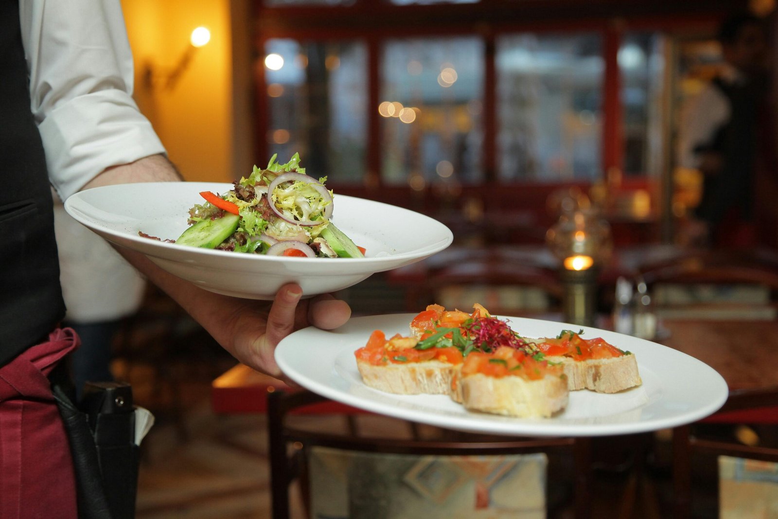 Makati Manila City Tourism: Must Visit Spots and Local Experiences 3 A waiter serves a fresh salad and hors d'oeuvres in a cozy restaurant setting.