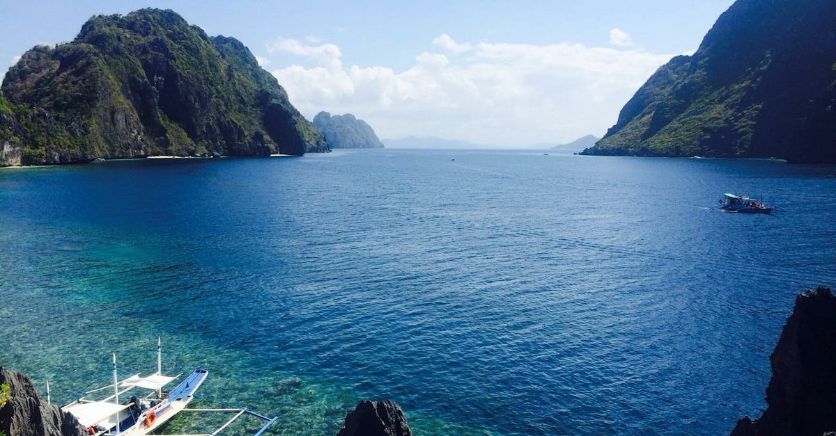 Crystal clear tropical lagoon with boats amidst stunning cliffs and deep blue waters.