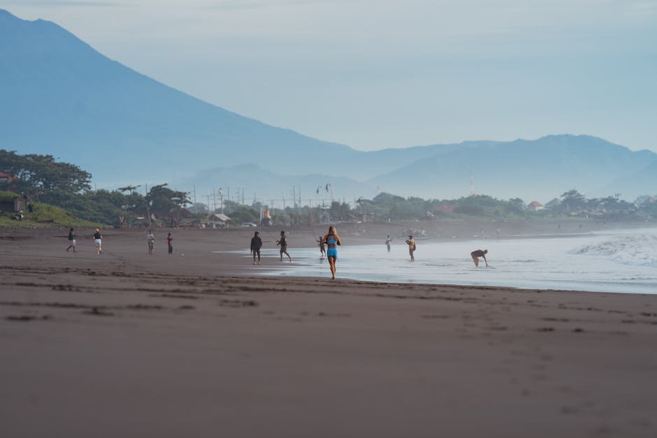 pexels-photo-15167059-15167059 People enjoying a peaceful walk on Sanur beach with scenic mountains in the background. Bali Beach scene