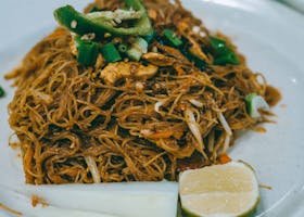 Savor a plate of authentic stir-fried Asian noodles, garnished with fresh lime and green peppers.