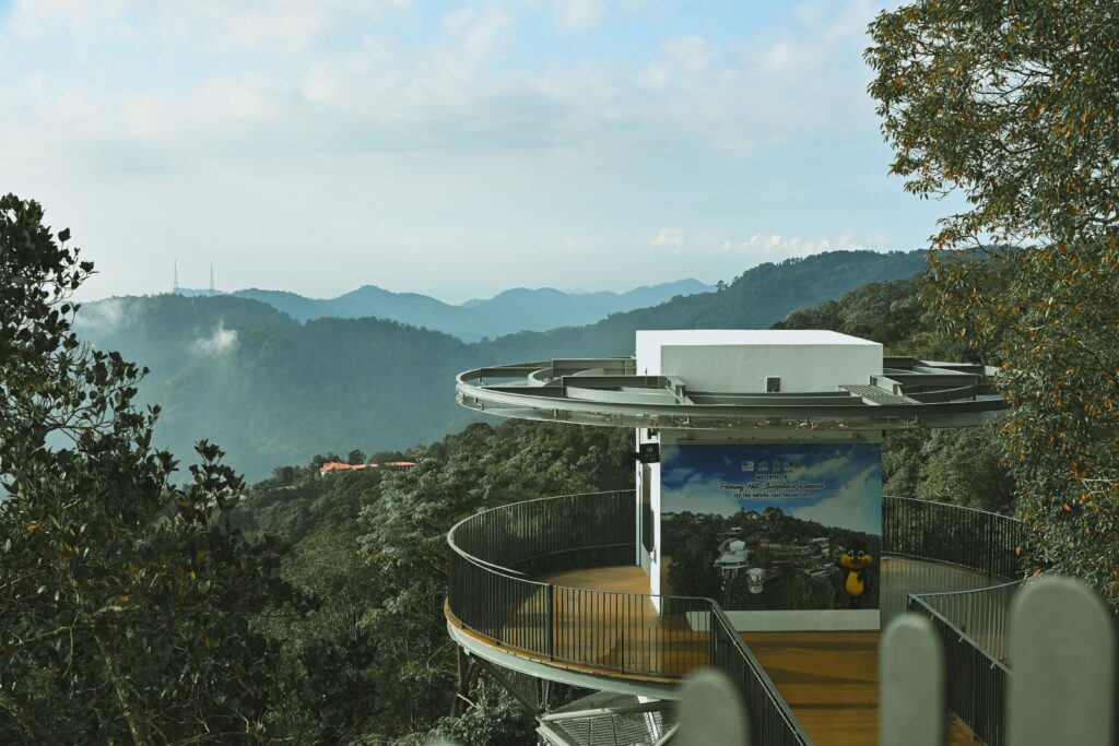 Observation deck amidst lush greenery in Penang Hills, offering a panoramic view of the misty mountains.